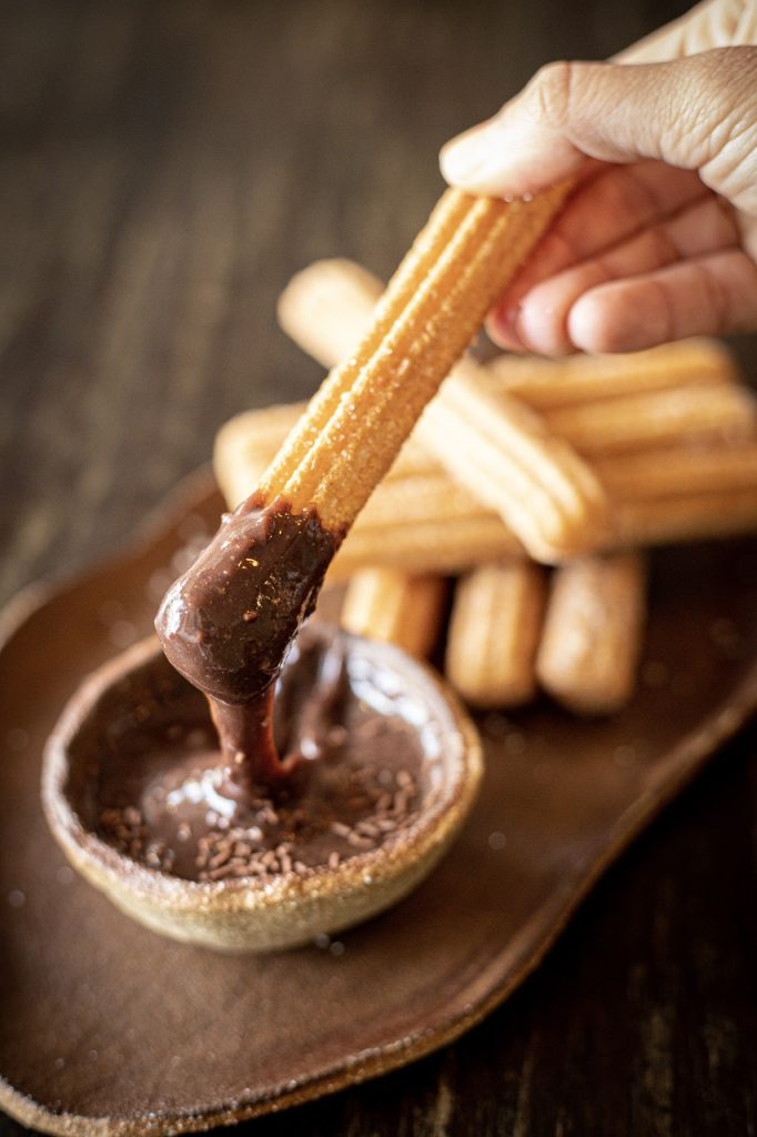 Churros: Tarçın ve Çikolatanın Büyülü DansıSpanish tapas churros with sugar and chocolate sauce. Dark backg